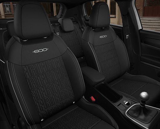 Auf diesem Bild ist der schwarze Innenraum eines Autos zu sehen, mit den vorderen Sitzen, die mit einem '-600-' Schriftzug und einem eingeprägten 'FIAT'-Muster versehen sind, sowie einer Mittelkonsole mit manuellem Schaltknüppel.